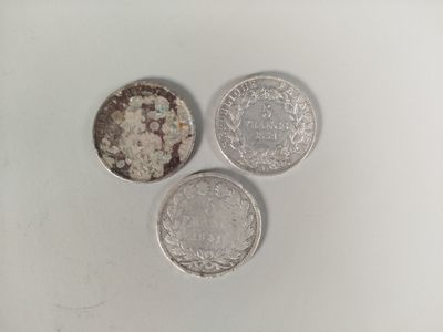 three silver coins sitting on top of each other on a white surface