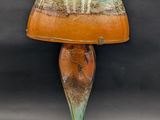 an orange and green lamp with a glass shade on top of it