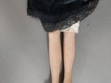 a doll that is wearing a black dress and brown shoes