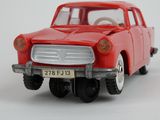 a red toy car that is sitting on a white surface