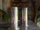 two silver vases sitting on top of a table