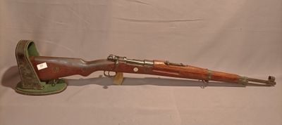 un vieux fusil exposé sur une surface blanche avec un fond blanc