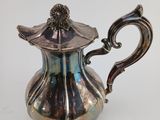 an antique silver tea pot with a handle on a white surface