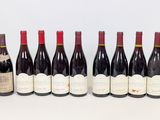 six bottles of wine lined up in a row on a white surface