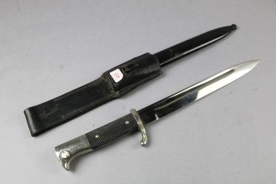 pair of knives with leather sheaths on a white surface