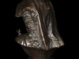 bronze bust of a man with a hat and cloak on a black background