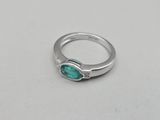 a close up of a silver ring with a green stone