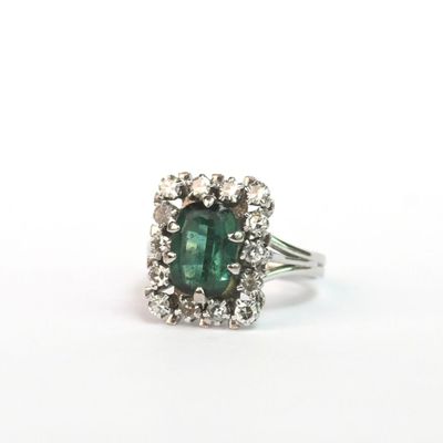 un gros plan d'une bague en tourmaline verte et diamants sur fond blanc