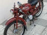 a red motorcycle parked next to a building on the sidewalk