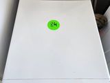 un lave-linge et un sèche-linge blancs dans un garage, sur lesquels est apposé un autocollant vert