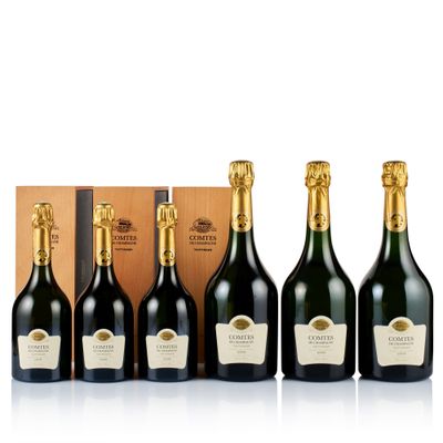 a group of six bottles of champagne in front of a wooden box