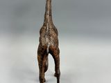 statue d'une girafe debout sur une surface blanche, avec un fond gris