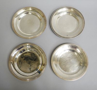 quatre assiettes plaquées argent posées sur une table à fond blanc