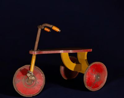 tricycle en bois jaune et rouge sur fond bleu foncé