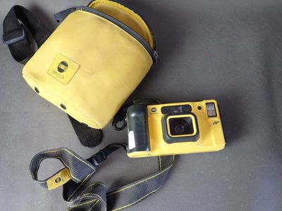 un appareil photo jaune et un sac jaune posés par terre