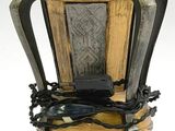 un vase en bois muni d'une poignée en métal et posé sur un socle
