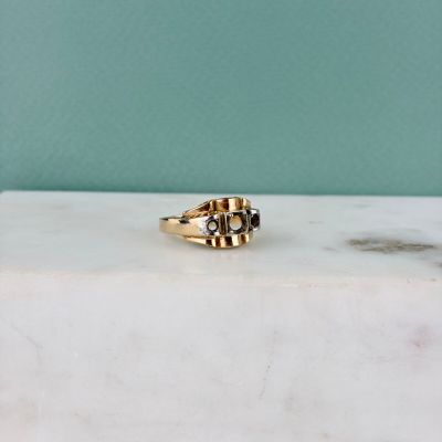 un gros plan d'une bague en or posée sur une surface en marbre