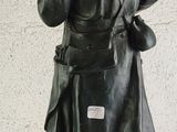 bronze statue of a man holding a gun on a white surface