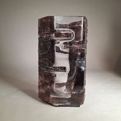un vase en verre muni d'une poignée en métal, posé sur une table