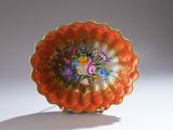 une assiette orange décorée de fleurs, posée sur une surface blanche