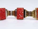 pair of red and gold cuff bracelets on a white surface