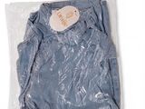 La chemise bleue est emballée dans du plastique et porte une étiquette