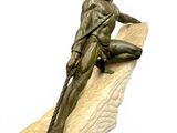 statue of a man sitting on a rock with a spear