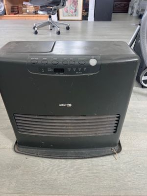 un purificateur d'air posé sur un parquet, à côté d'une chaise