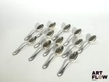six silver spoons are lined up in a row on a white surface