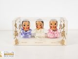 three figurines in a clear box on a white surface