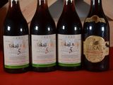 four bottles of wine are lined up on a red table
