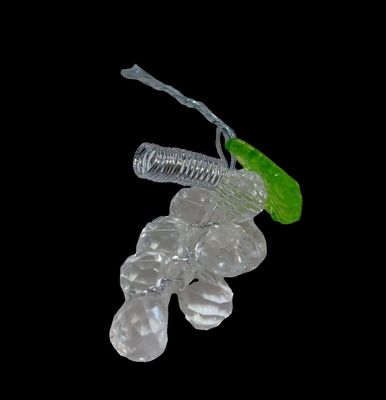 a glass figurine with a green leaf on top of it