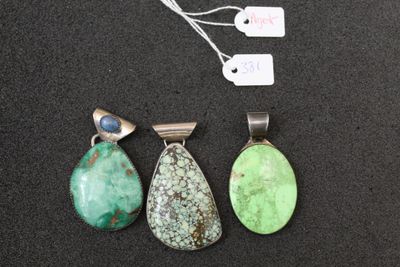 three pendants of different colors and shapes on a black surface