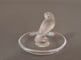 a glass figurine of a bird sitting on a glass plate