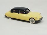 yellow toy car with black top and white wheels on a white surface