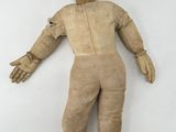 a wooden doll with a hat and boots on a white surface