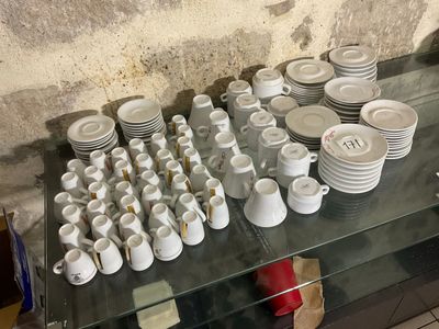 many cups and saucers sitting on a glass shelf
