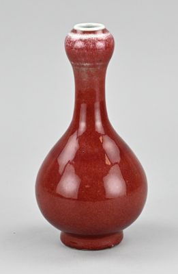 une photo d'un vase rouge posé sur une table blanche