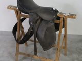 a black saddle on a wooden stand in a room