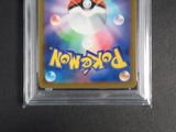the pokemon card is in a clear plastic holder on a black surface