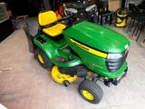 a green and yellow lawn mower parked in a garage