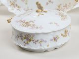 a white plate with a bird on it and a bowl with a lid