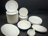 beaucoup d'assiettes et de bols blancs sur la table