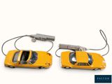 two yellow toy cars connected to each other on a white surface