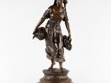 une statue en bronze représentant une femme tenant un panier de fleurs