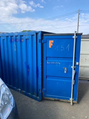 un conteneur bleu posé au milieu d'un parking
