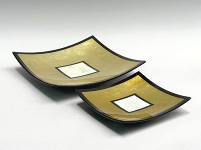 two black and gold bowls with square designs on them