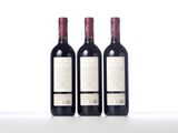 three bottles of red wine sit side by side on a white surface