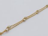a close up of a gold chain bracelet with pearls on it