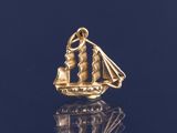 une image représentant un pendentif en forme de voilier plaqué or sur un fond noir